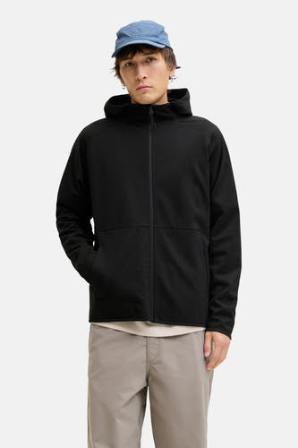 Gilet noir de CORE BY JACK & JONES, avec des manches longues et un capuchon, associé à une casquette bleue et à un pantalon gris.