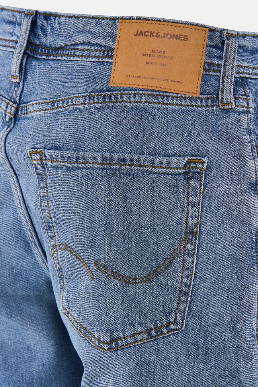 Short en jean de couleur bleu moyen de JACK & JONES JEANS INTELLIGENCE, avec surpiqûres marron, poche arrière et étiquette de marque en cuir.