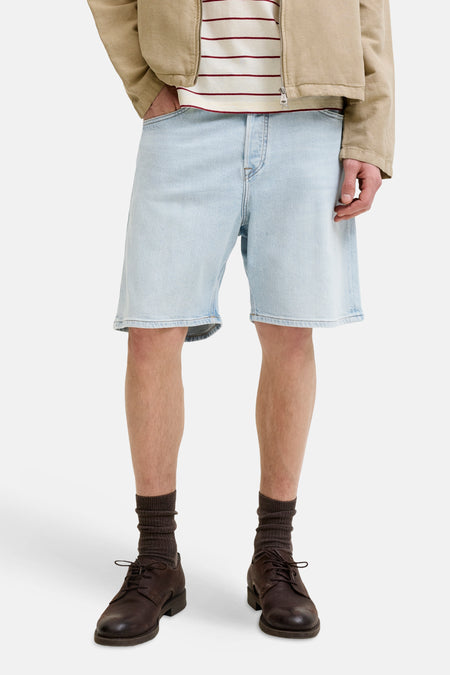 Short en jean en denim bleu clair de JACK & JONES JEANS INTELLIGENCE, avec bords effilochés, porté avec une veste beige et un haut rayé.