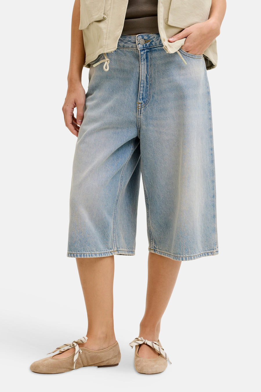 Short en jean bleu clair de JJXX, combiné avec un gilet kaki et des ballerines marron.