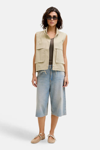 Korte lichtblauwe denim short van JJXX, gecombineerd met een mouwloos vest en ballerina's met strik.
