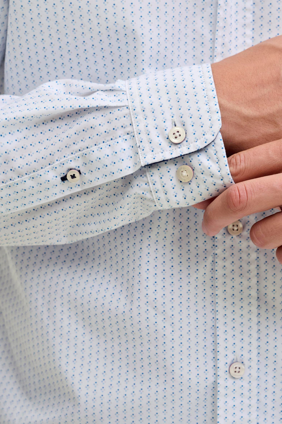 Wit overhemd met blauwe stippen en knopen.