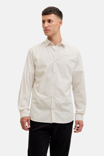Chemise beige à longues manches de PREMIUM by JACK & JONES, portée sur un T-shirt blanc et un pantalon noir.