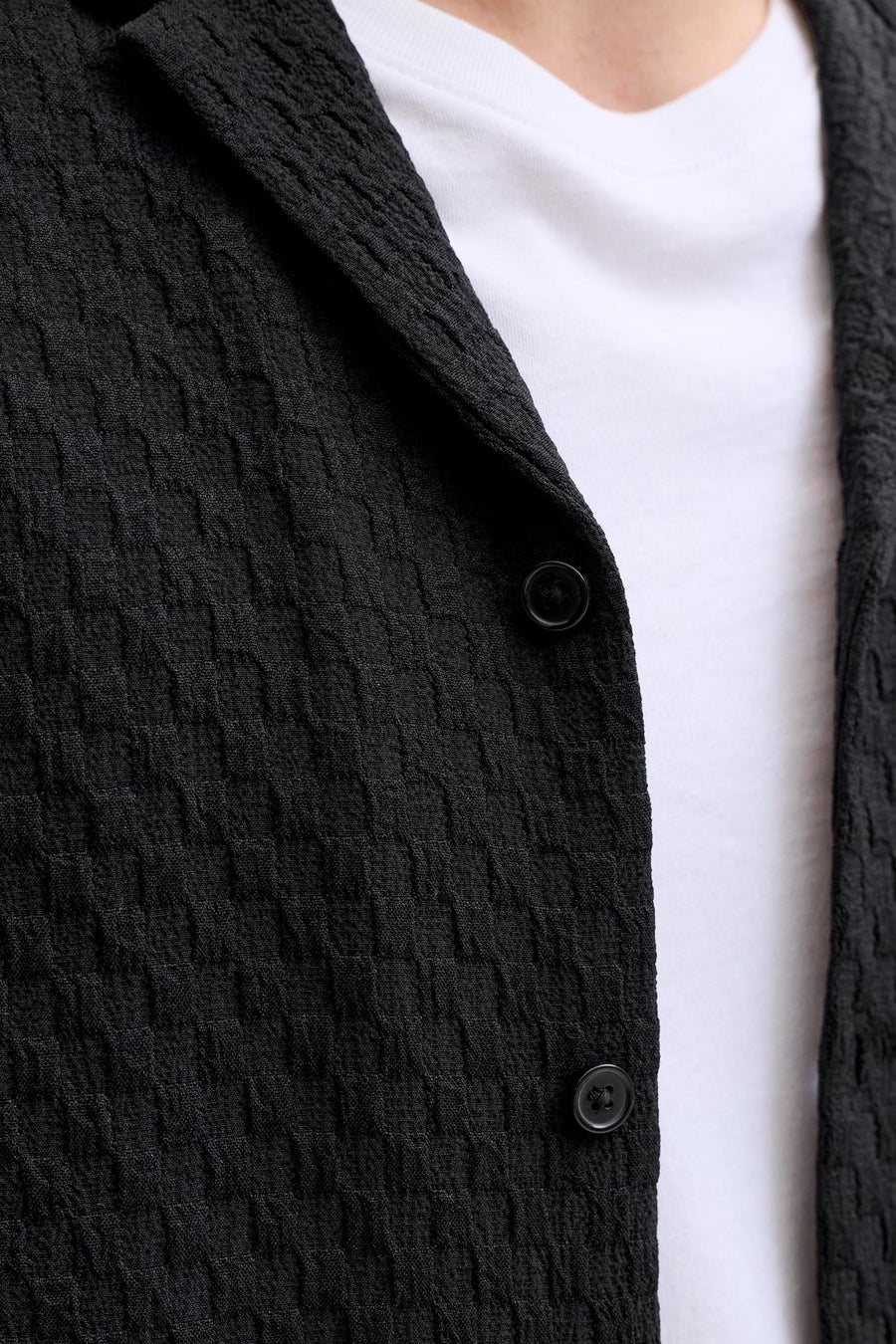 Chemise noire de CORE BY JACK & JONES, à manches courtes et à la texture subtile, portée sur une chemise blanche.