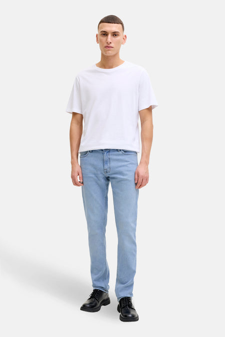 Man met wit T-shirt, blauwe jeans en zwarte schoenen.