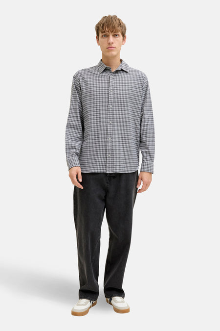 Grijs, lange mouwen hemd van JJREBEL, met een kleine ruit, gedragen met een donkere broek en witte sneakers.
