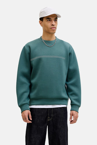 Pull bleu à col rond de CORE BY JACK & JONES, avec des rayures horizontales et combiné avec un jean ample et une casquette.