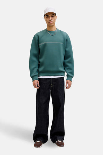 Blauwe sweater met ronde hals van CORE BY JACK & JONES, met horizontale strepen en gecombineerd met wijde jeans en een pet.
