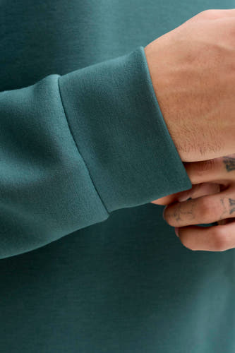 Pull bleu de CORE BY JACK & JONES, à manches longues et avec une main visible tatouée.
