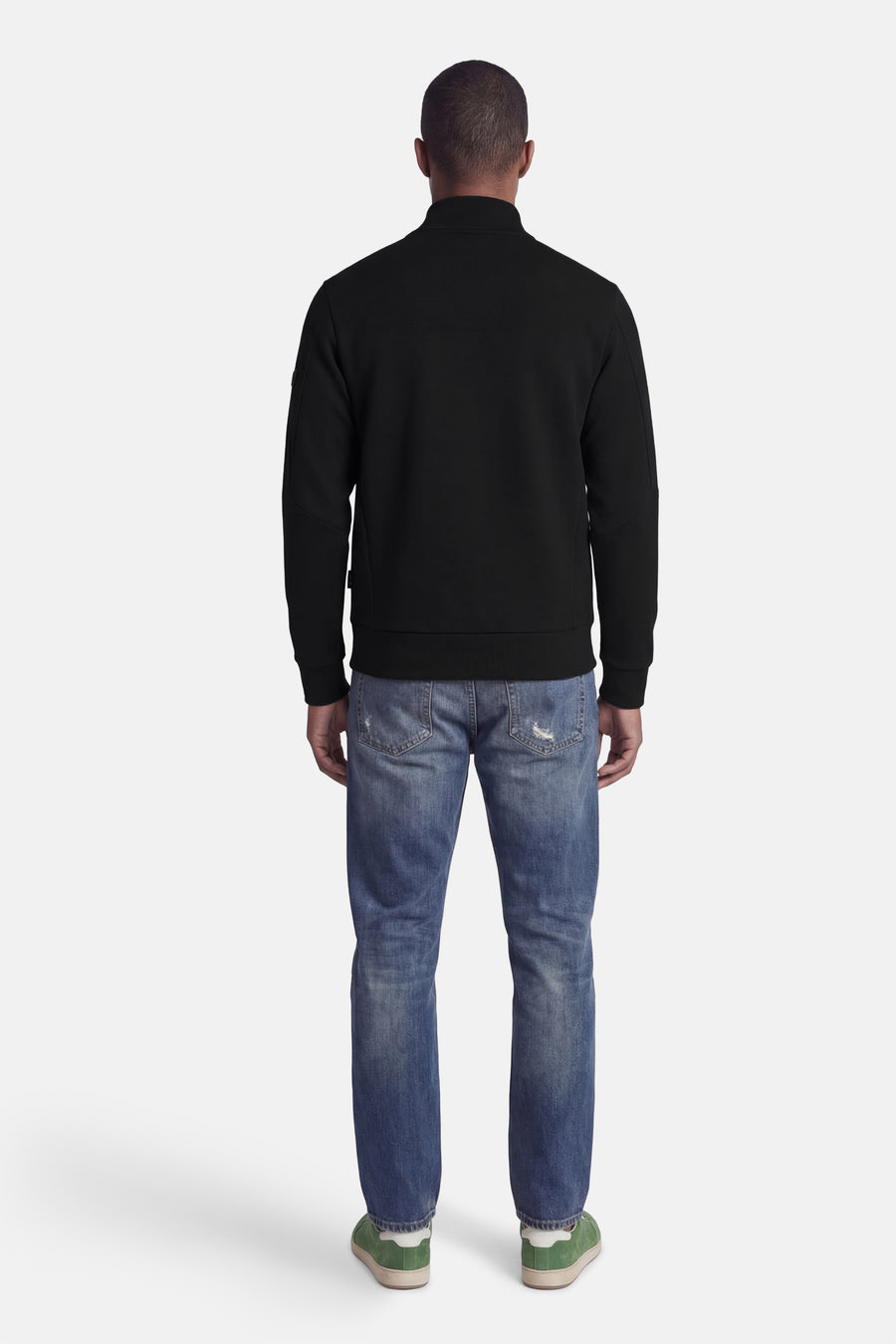 Zwarte korte jas van CORE BY JACK & JONES, gezien van achteren, met blauwe jeans en groene schoenen.