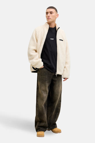 T-shirt noir à manches courtes de CORE BY JACK & JONES, avec un petit logo, porté sous un gilet teddy et des jeans larges avec des bottes.