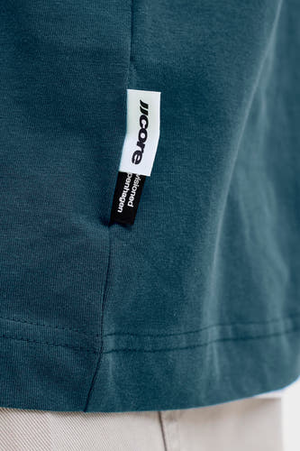 T-shirt bleu à manches courtes de CORE BY JACK & JONES, gros plan sur l'étiquette avec le nom de la marque sur tissu uni.