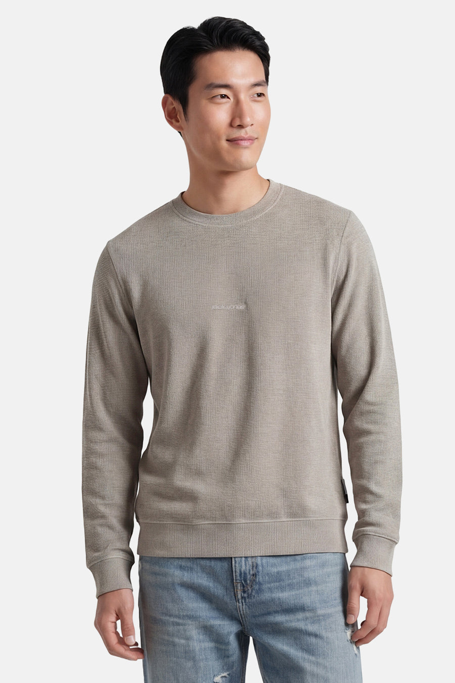 Pull gris à col rond de CORE BY JACK & JONES, avec une texture fine et un logo discret sur la poitrine, porté avec un jean clair.