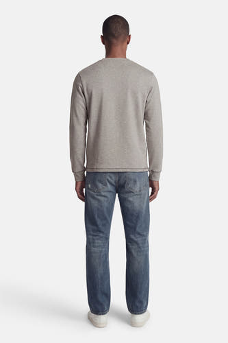 Pull gris de CORE BY JACK & JONES, à manches longues, col rond et poignets côtelés, porté de dos sur un jean bleu et des baskets blanches.