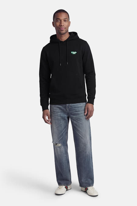 Sweat à capuche noir de CORE BY JACK & JONES, avec logo bleu sur la poitrine et combiné avec un jean déchiré et des baskets basses.