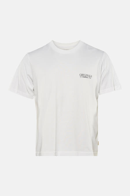 T-shirt blanc à manches courtes de ORIGINALS BY JACK & JONES, avec un petit logo sur la poitrine, porté avec un jean déchiré.