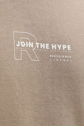 Pull marron de JJREBEL, avec texte blanc et logo sur la poitrine, sur un fond texturé.