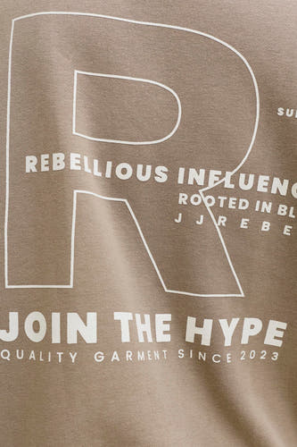 Pull marron de JJREBEL, avec un grand R blanc et le texte "JOIN THE HYPE".