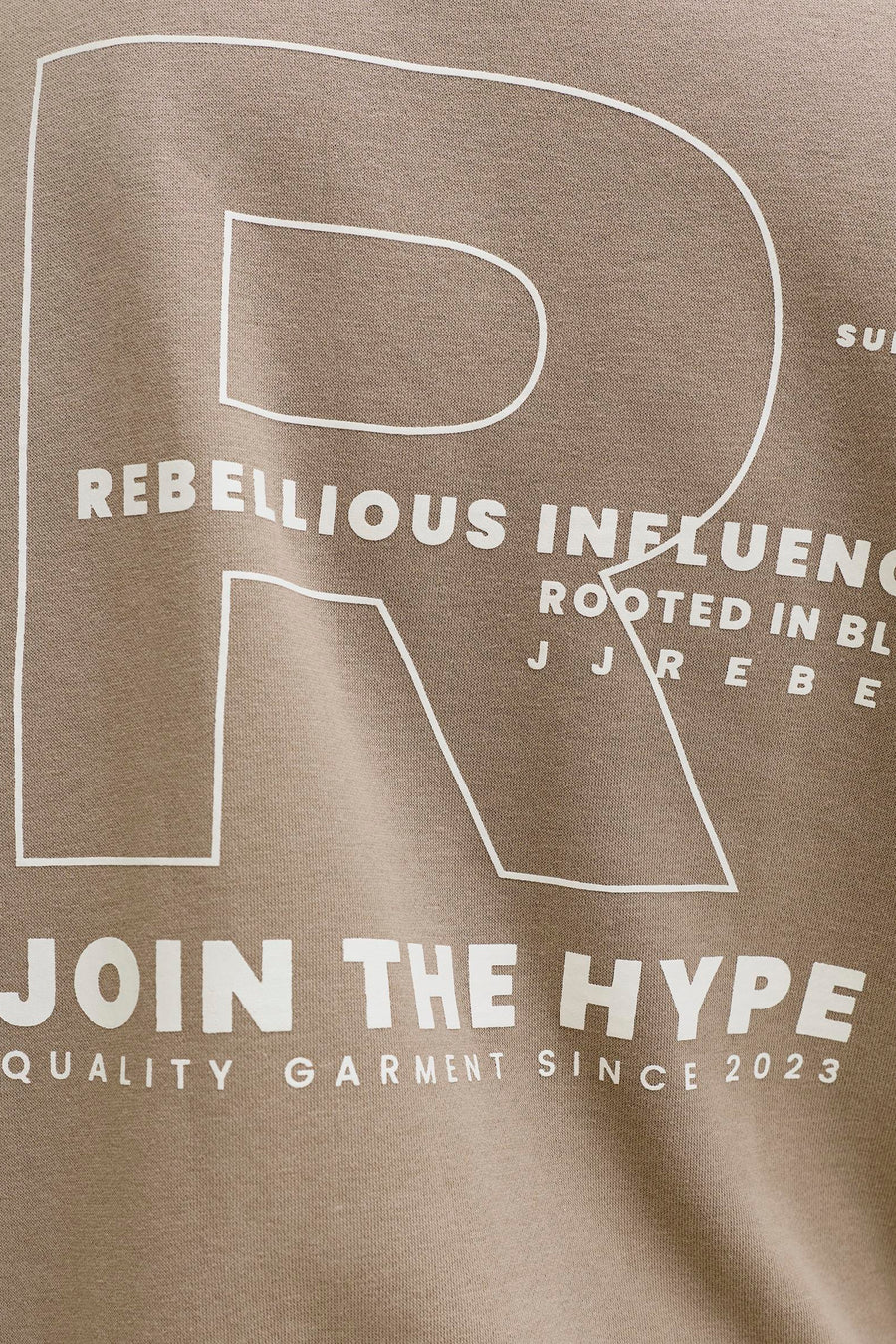 Pull marron de JJREBEL, avec un grand R blanc et le texte "JOIN THE HYPE".