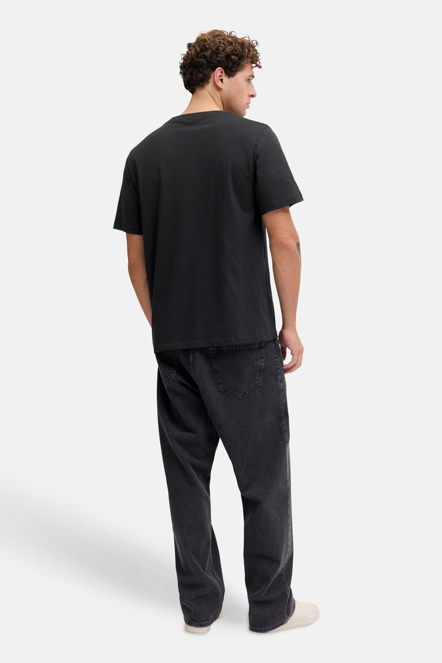 T-shirt noir à manches courtes de JJREBEL, vu de dos, avec un jean foncé et des chaussures claires.