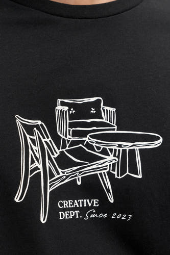T-shirt noir à manches courtes de JJREBEL, avec illustration blanche de meubles et le texte "Creative Dept. Since 2023".