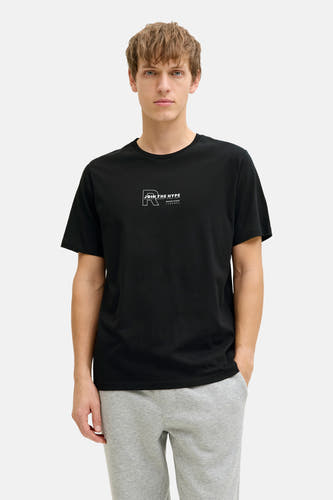 T-shirt noir à manches courtes de JJREBEL, avec imprimé texte blanc, porté avec un jogging gris.
