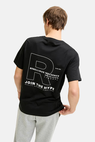 T-shirt noir à manches courtes de JJREBEL, avec imprimé texte blanc au dos, combiné avec un jogging gris.