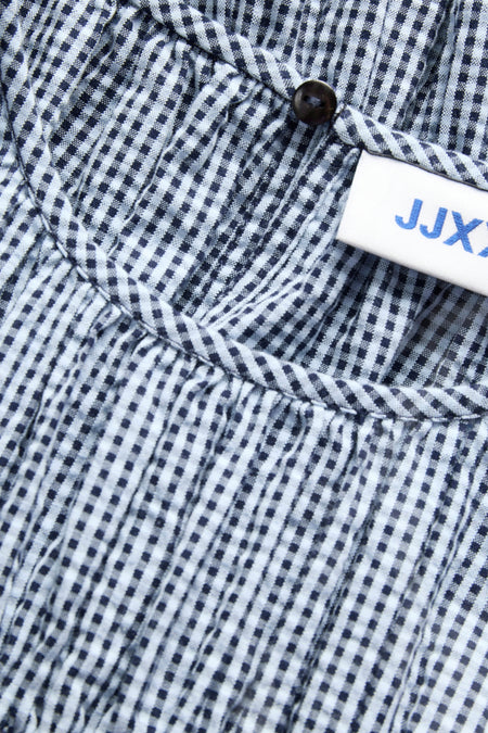 Chemise à manches longues à carreaux bleus de JJXX, avec un détail de bouton et une étiquette.