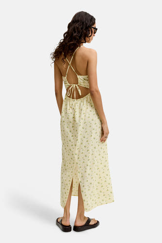 Robe sans manches jaune de JJXX avec imprimé fleuri à carreaux, découpe avec nœud au dos, fente latérale et sandales noires, vue arrière.