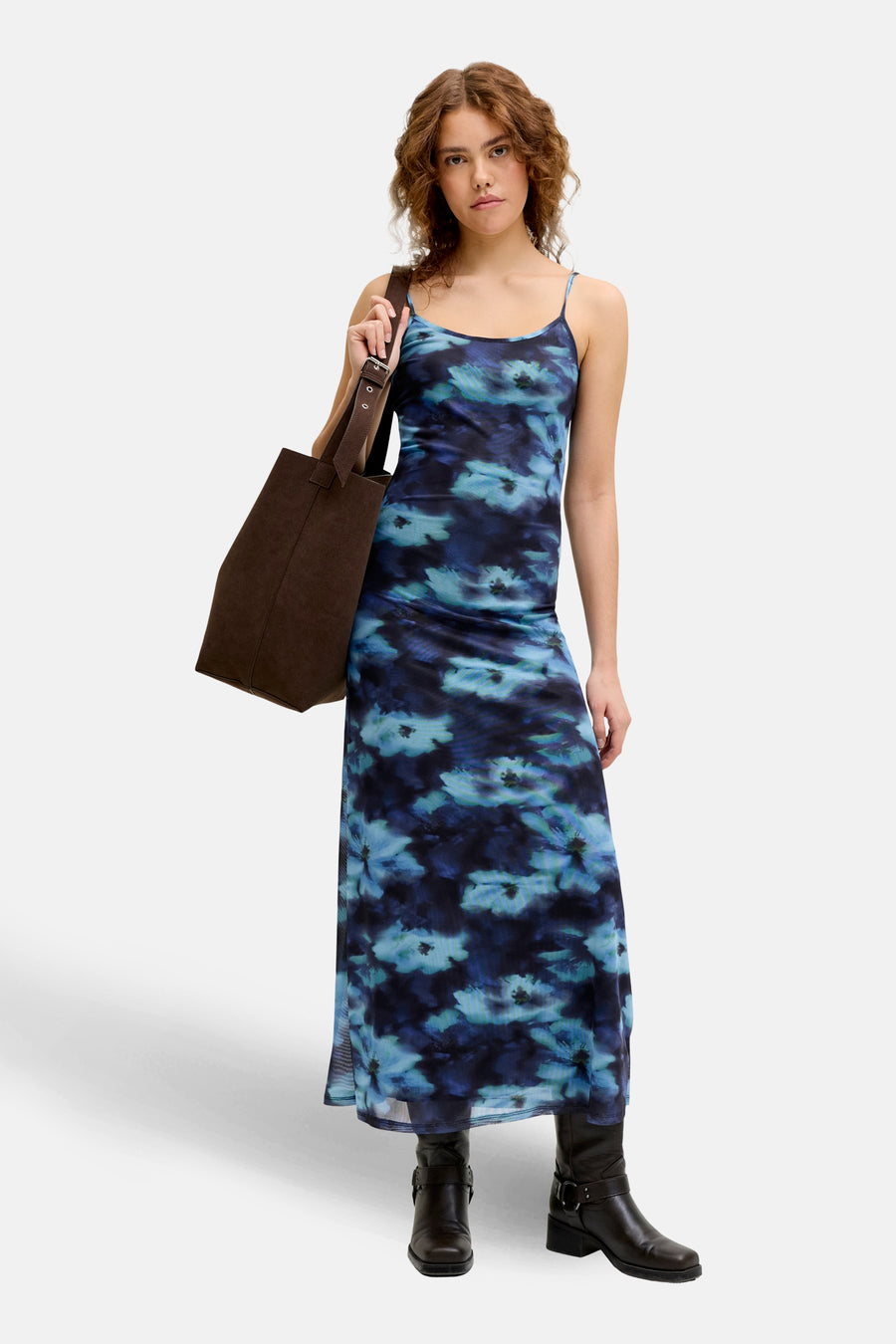 Robe bleue sans manches de JJXX, avec un motif floral et associée à des bottes et un sac marron.