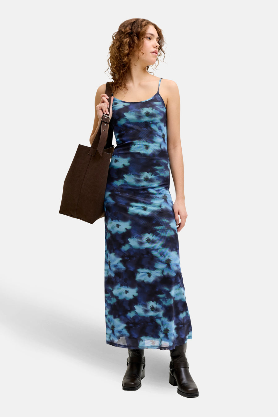 Blauw kleedje zonder mouwen van JJXX, met een bloemenpatroon en gecombineerd met laarzen en een bruine tas.