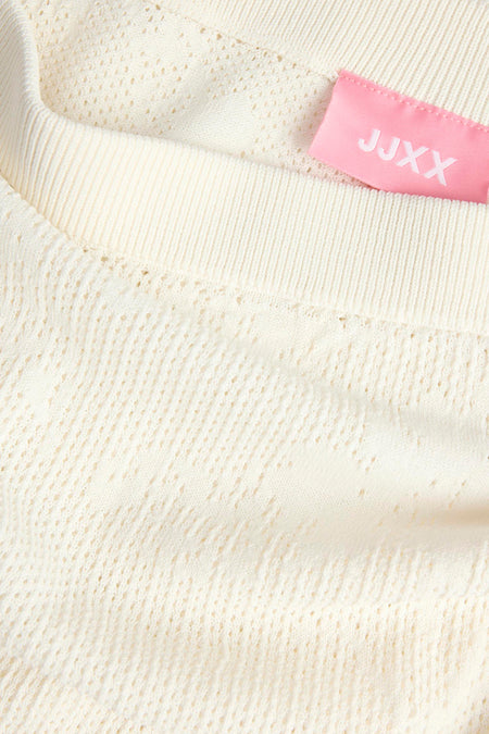 Jupe blanche JJXX à motif ajouré, bord côtelé et étiquette rose, en gros plan.
