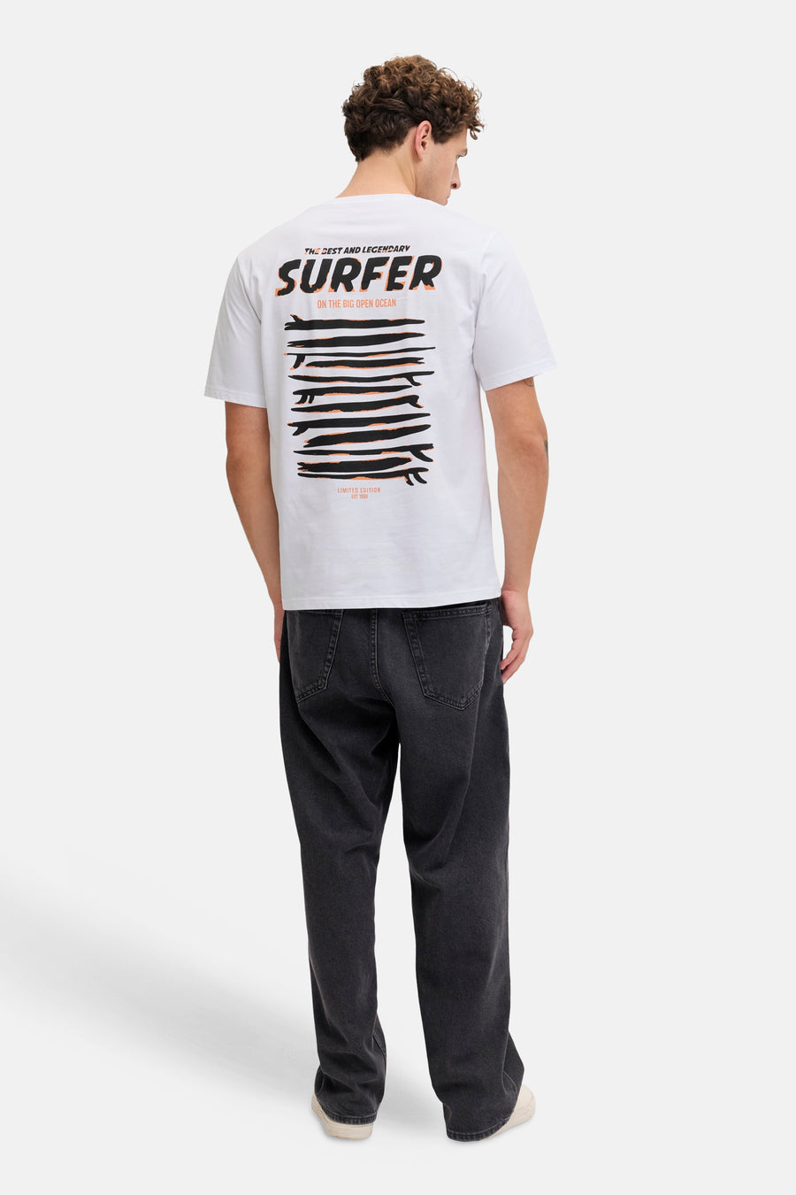 T-shirt blanc JJREBEL, avec un imprimé surfeur au dos, combiné avec un jean foncé et des baskets claires.