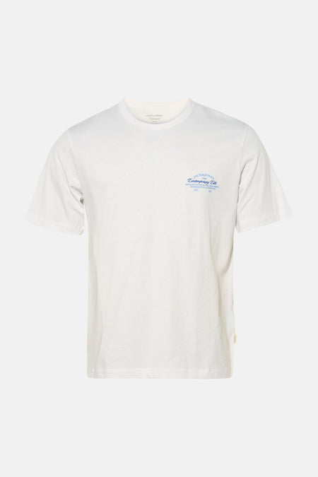 T-shirt blanc à manches courtes de ORIGINALS BY JACK & JONES, avec imprimé texte bleu sur la poitrine, porté avec un jean gris foncé et des baskets blanches.