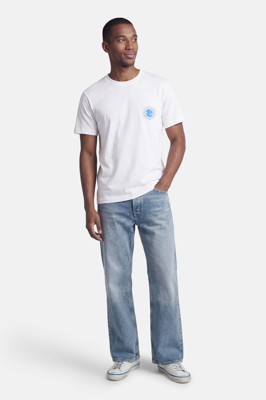 T-shirt blanc à manches courtes de ORIGINALS BY JACK & JONES, avec col rond et imprimé logo sur la poitrine, porté avec un jean et des baskets.