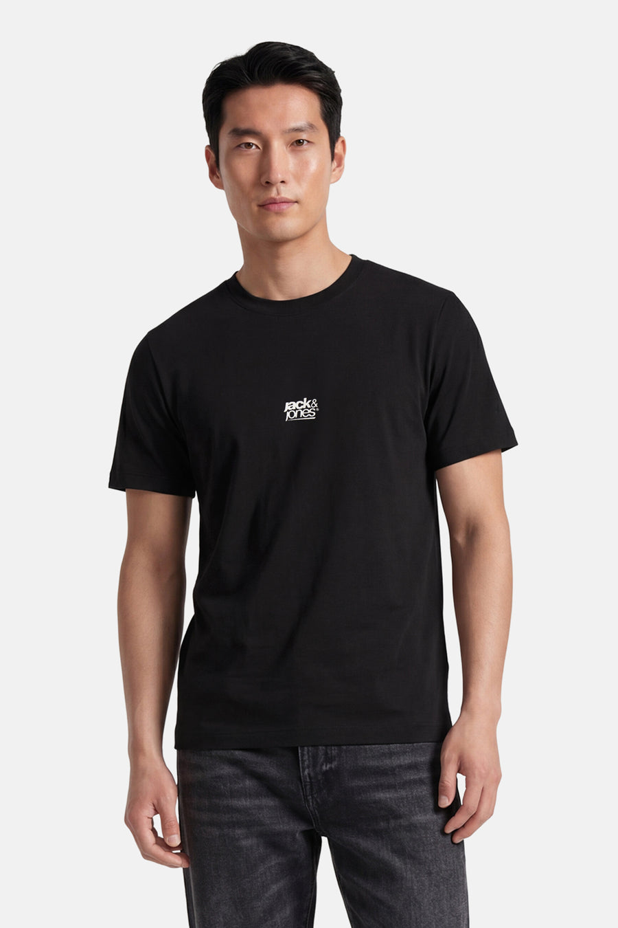 T-shirt noir de CORE BY JACK & JONES avec logo Jack & Jones blanc sur la poitrine, porté par un mannequin en jean foncé.