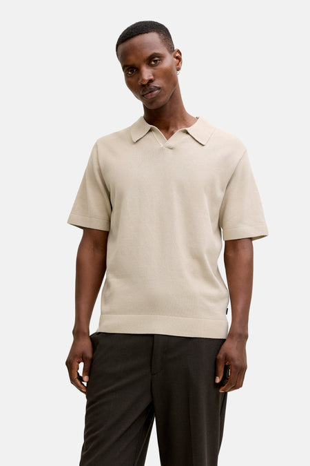 Polo beige à manches courtes de PREMIUM by JACK & JONES, avec une texture finement tricotée, combinée avec un pantalon foncé et des mocassins marron.