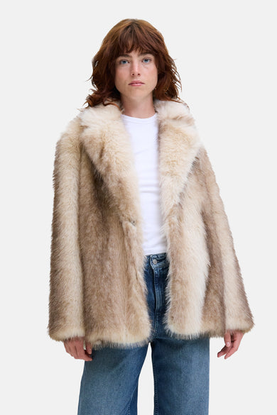 Gilet écru de JJXX, porté sur un t-shirt blanc et des jeans bleus.