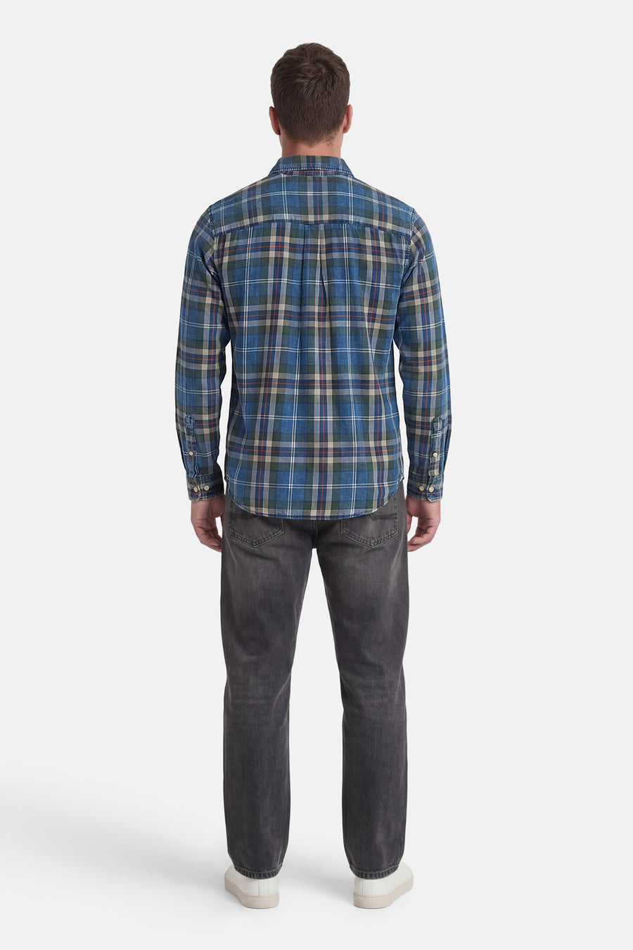 Chemise à carreaux bleus à manches longues de JACK & JONES, portée par un homme avec un jean foncé et des baskets blanches, vue de dos.