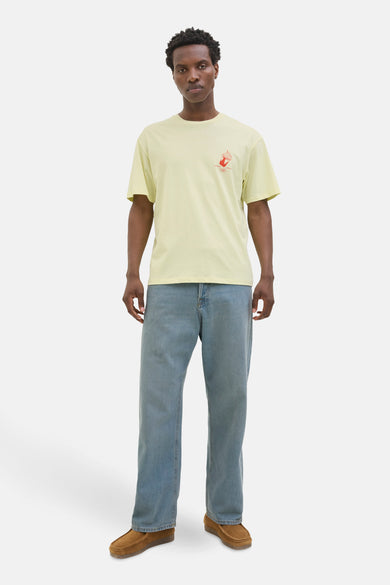 T-shirt jaune à manches courtes d'ORIGINALS BY JACK & JONES, avec une petite impression rouge et associé à des jeans bleus et des loafers marrons.