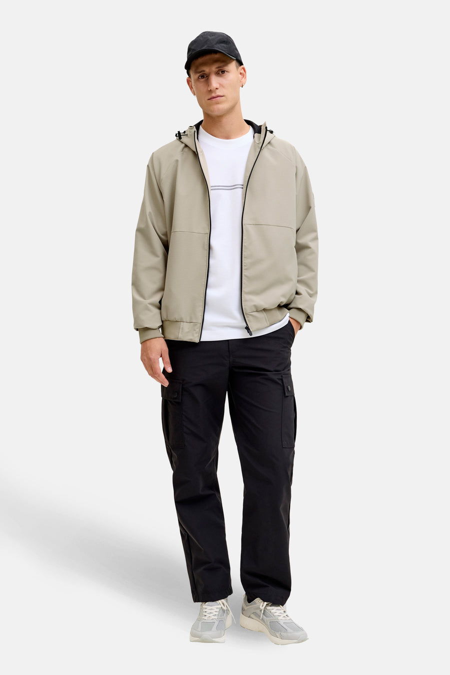 Manteau court beige de CORE BY JACK & JONES, avec fermeture éclair et capuche, combiné avec un pantalon noir et un T-shirt blanc.