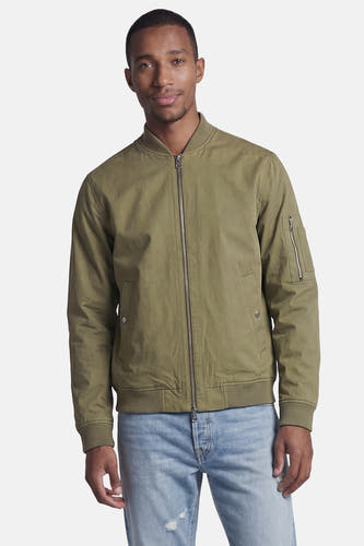 Veste courte verte de CORE BY JACK & JONES, style bomber avec fermeture éclair, poignets côtelés et poche sur la manche, portée par un homme.