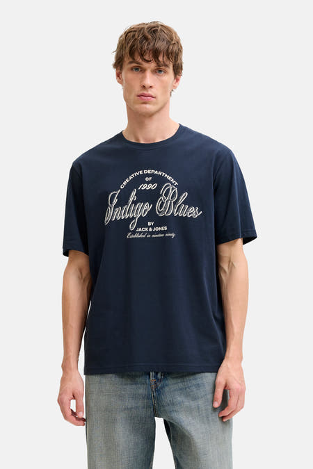 T-shirt bleu à manches courtes d'ORIGINALS par JACK & JONES, avec une impression blanche sur la partie avant, associé à des jeans larges et des mocassins.
