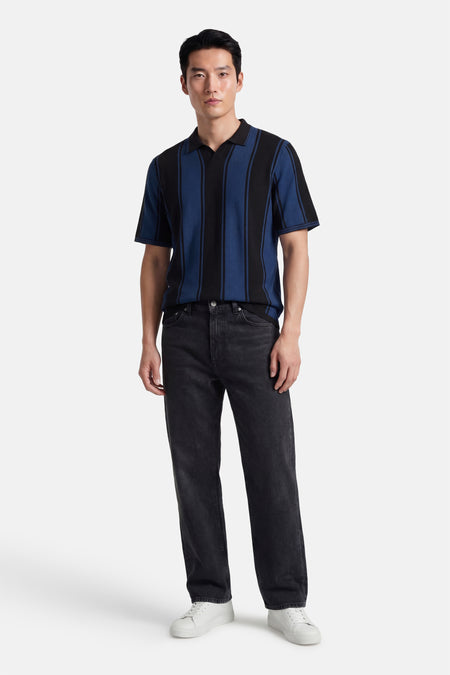 Polo multicolore à manches courtes de CORE BY JACK & JONES, avec des rayures noires et bleues, combinée avec un jean noir et des baskets blanches.