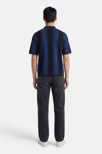 Polo noire à manches courtes de CORE BY JACK & JONES, dos, avec des rayures blanches sur le col et les manches, combinée avec un jean.