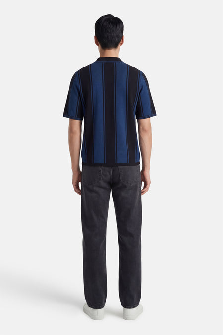 Polo noire à manches courtes de CORE BY JACK & JONES, dos, avec des rayures blanches sur le col et les manches, combinée avec un jean.