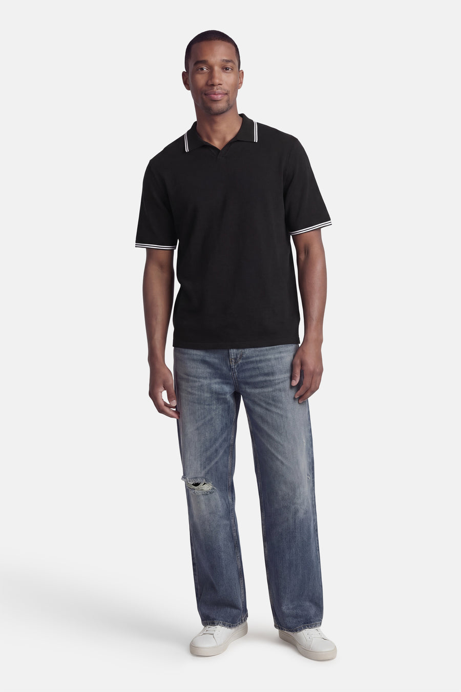 Polo noire à manches courtes de CORE BY JACK & JONES, avec des accents blancs et combinée avec un jean et des chaussures blanches.