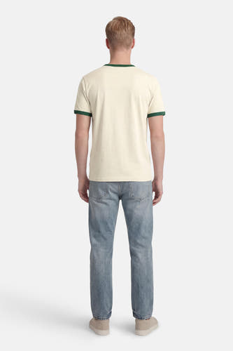 T-shirt beige à manches courtes de ORIGINALS BY JACK & JONES, avec des accents verts au col et aux manches, porté avec un jean et des baskets.