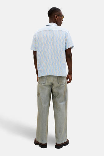 Chemise bleue à manches courtes de ORIGINALS BY JACK & JONES, avec un motif géométrique, vue de dos, combinée avec un jean et des chaussures marron.