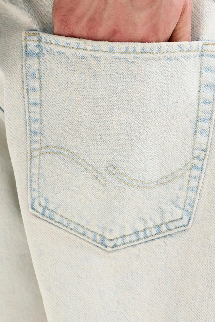 Short en jean bleu clair de JACK & JONES JEANS INTELLIGENCE avec une main dans la poche arrière et des surpiqûres jaunes.